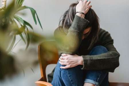 Bild på en kvinna som sitter ihopkrupen på en stol som refererar till oron att få ett positivt drogtest för cannabis (THC).